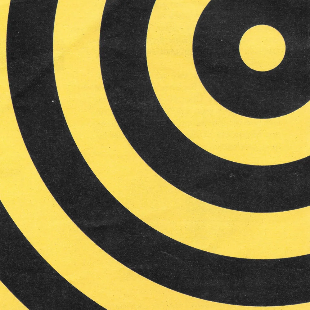 Scan of a printed page: black concentric rings on yellow paper, the bullseye off in the top right corner and the outer rings running off all four edges, the paper grain showing through the solid ink