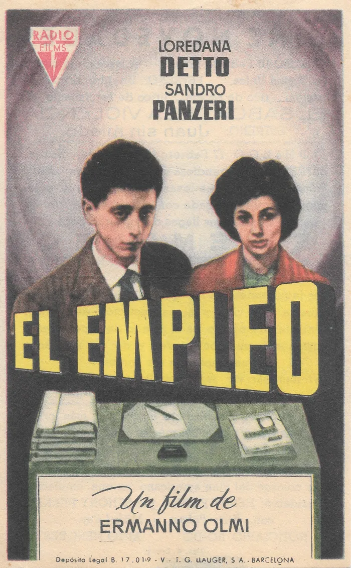 Scan of a Spanish film handbill for Ermanno Olmi's «El empleo»: a young man and woman behind an office desk, the title in yellow block capitals, with the print on the back showing through the thin paper